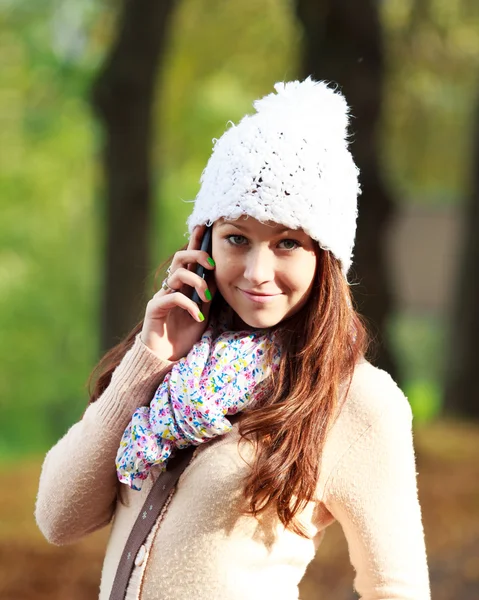 Mulher bonita falando no novo telefone celular no parque de outono Imagens De Bancos De Imagens Sem Royalties