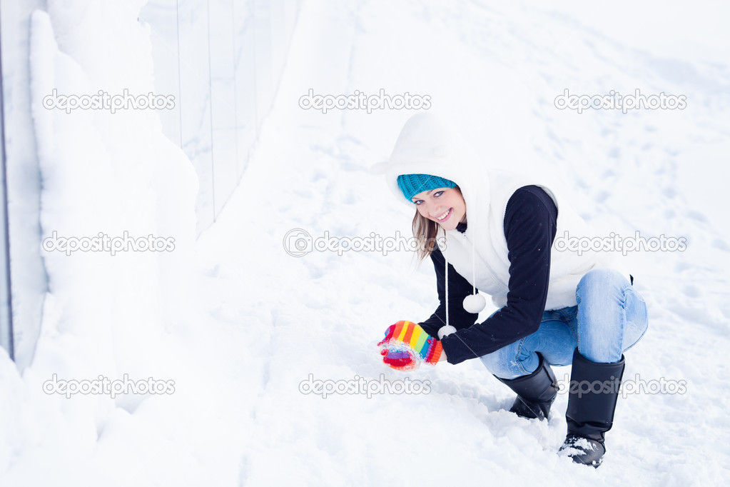 Beautiful GIrl in winter clothes preparing snow ball.