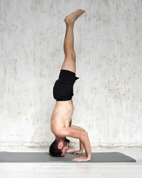 Un joven está haciendo yoga. Entrenador de yoga sobre un fondo ligero. —  Fotos de Stock