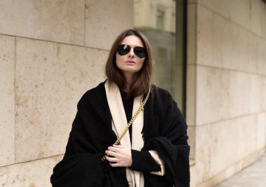 Geniş pencereli beyaz bir binanın arka planında şık bir kız. Şehir tarzı.