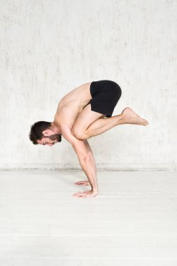 Genç bir adam yoga yapıyor. Yoga koçu hafif arka planda. Spor aktiviteleri.