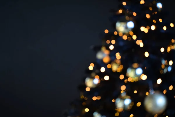 Размытое прошлое. Рождественский фон с огнями. Рождественские лампочки. Размытый силуэт рождественской елки Стоковое Фото