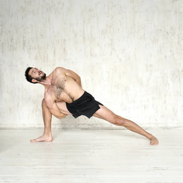 Un joven está haciendo yoga. Entrenador de yoga sobre un fondo ligero. — Foto de Stock