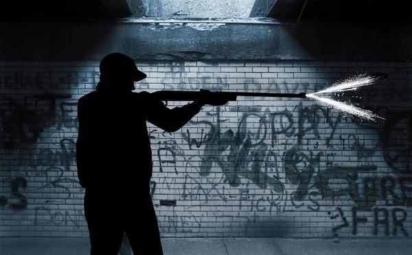 A silhouetted man is seen firing a gun in a dark spot under an overpass in a city in this 3-d illustration about urban violence.