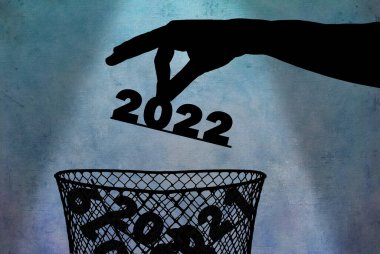 Bir el, siluet 2022 sayısını zaten geçmiş yılların numaralarını içeren bir çöp kutusuna atar..