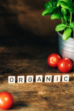 Koyu ahşap arka plan, harfler, taze fesleğen ve domates..