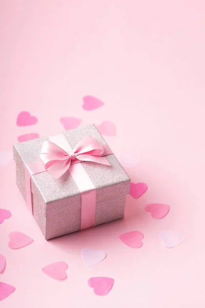 Caixa de presente glitter prata com laço de fita rosa sobre fundo rosa com confete. — Fotografia de Stock