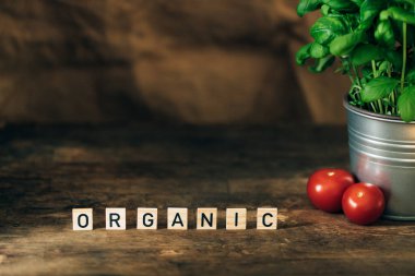 Koyu ahşap arka plan, harfler, taze fesleğen ve domates..