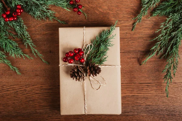 Gift box with winter decor on wooden table.