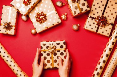 Altın fiyonklu hediye kutuları ve kırmızı arka planda kurdeleler..