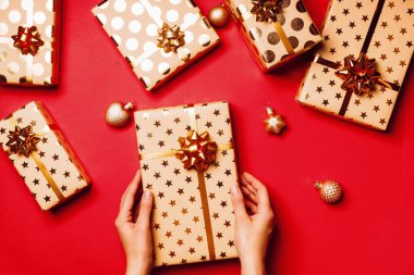 Altın fiyonklu hediye kutuları ve kırmızı arka planda kurdeleler..