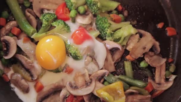 De groenten worden gebakken en er wordt een ei van bovenaf toegevoegd — Stockvideo