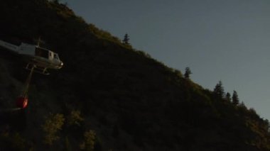 Yangın söndürme helikopteri ağır çekimde gün batımına doğru uçar.