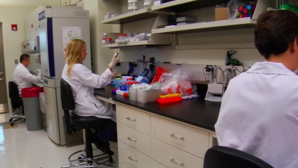 Dolly shot of scientists at work in laboratory — Stock Video