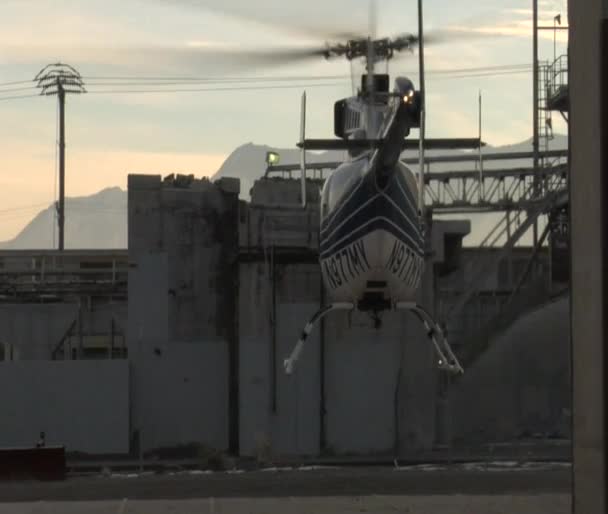 Helicopter lifts off and flies between buildings — Stock Video