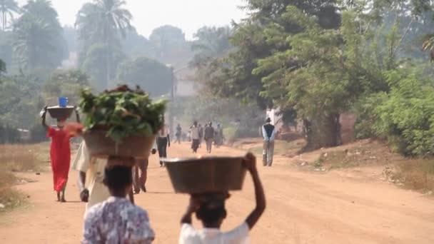Lantlig afrikanska väg med människor som bär produkter på huvud — Stockvideo