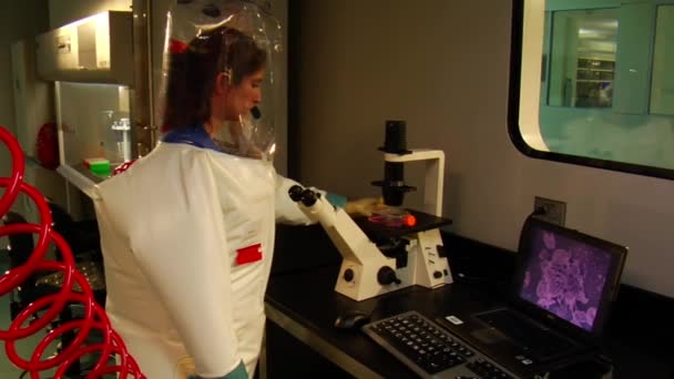 Scienziata donna in tuta bolla utilizza microscopio — Video Stock