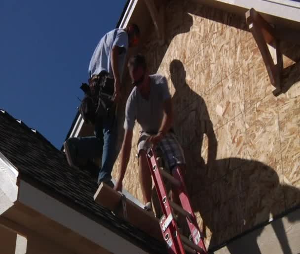 Men climb down ladder on house construction — Stock Video