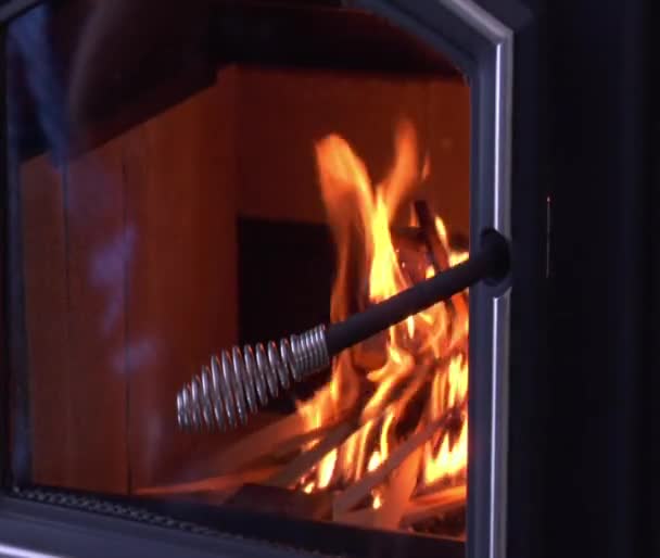 La mano cierra la puerta de cristal en la estufa de leña con fuego — Vídeos de Stock