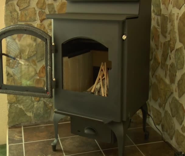 Man with baseball cap Starts fire in wood stove — Stock Video