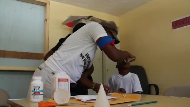Доктор дает лекарства ребенку в гаитянской клинике — стоковое видео