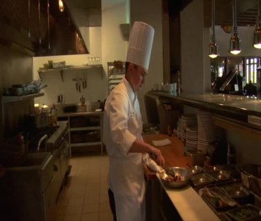 Şef yemek hazırlar ve yanan tavayla aşçılar