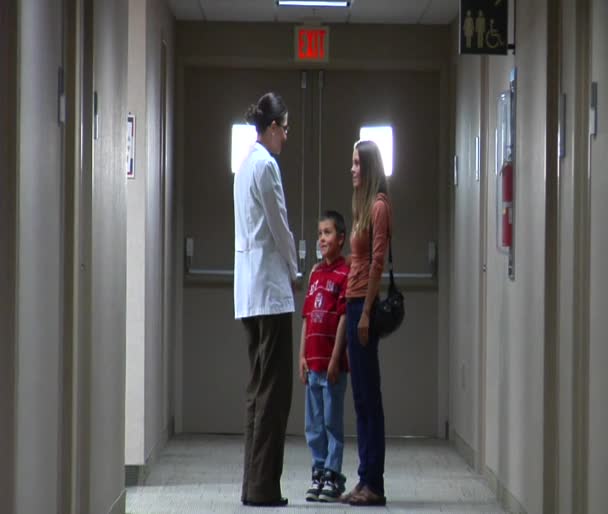 Doctor speaking to mom and son in hallway — Stock Video