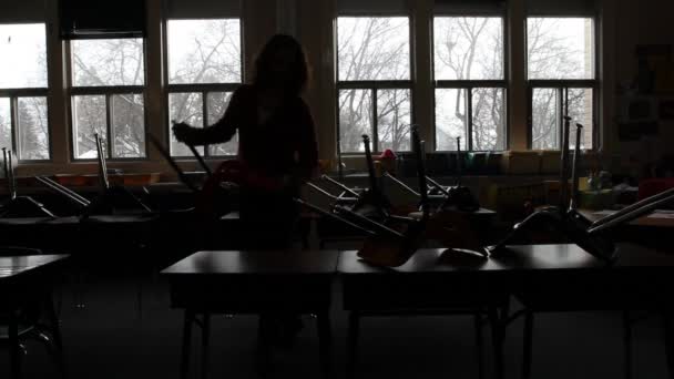 Учитель снимает стулья в классе — стоковое видео