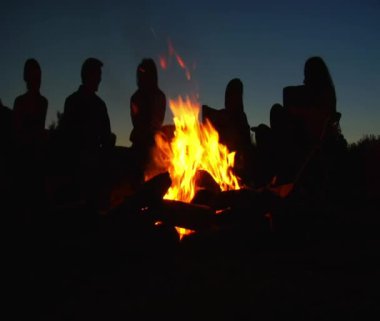 Kamp ateşi etrafında oturan insanlar