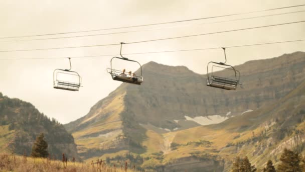 Sightseers on chairlift with mountain in distance — Stock Video