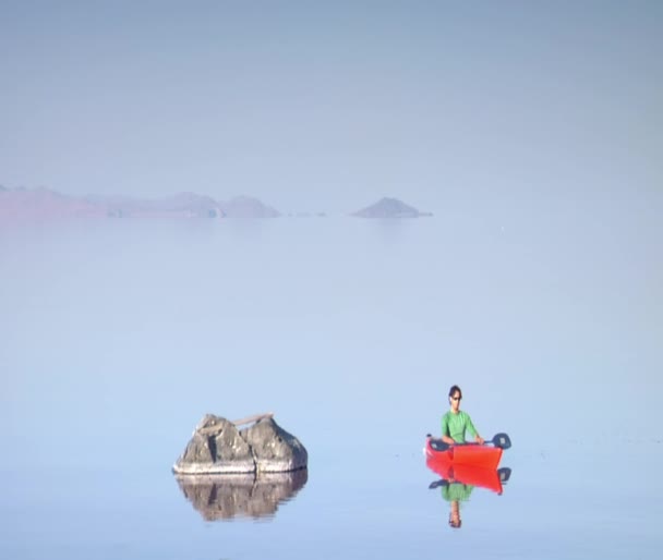 El hombre en kayak naranja deriva con la montaña en la distancia — Vídeo de stock