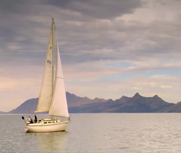Un voilier glisse sur l'eau calme près des montagnes 
