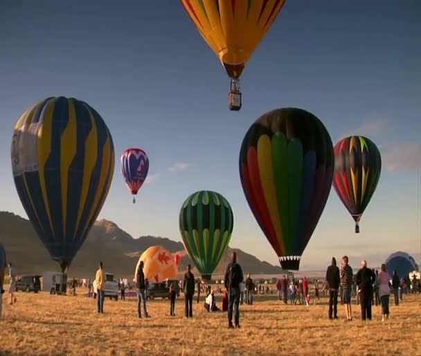 Zuschauer sehen zu, wie Heißluftballons in den Himmel steigen — Stockvideo