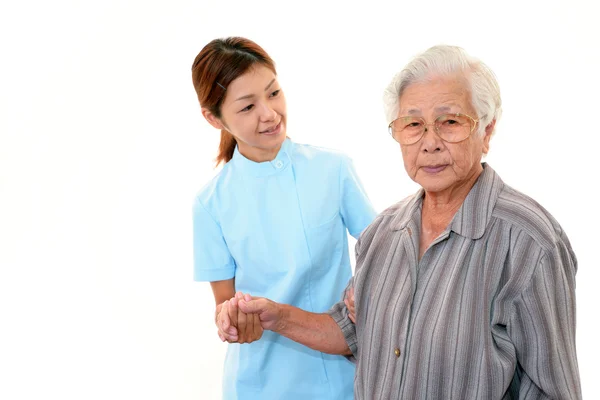 Vriendelijke verpleegster zorgt voor een oudere vrouw — Stockfoto