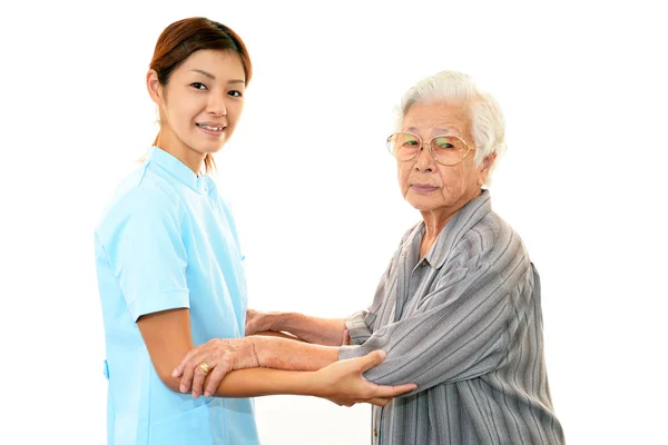 Freundliche Krankenschwester kümmert sich um eine ältere Frau — Stockfoto