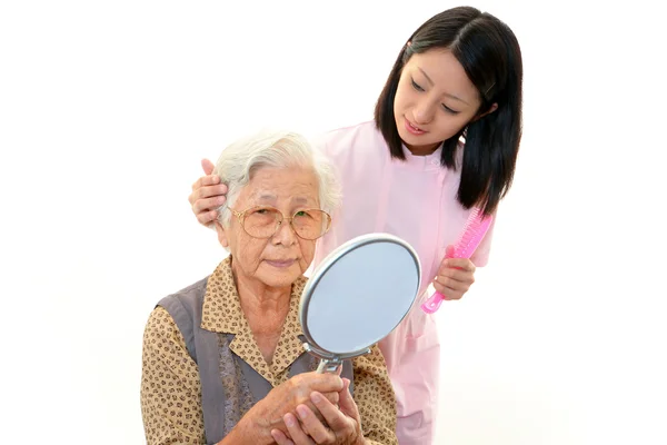 Vänliga sjuksköterskan bryr sig om en äldre kvinna — Stockfoto