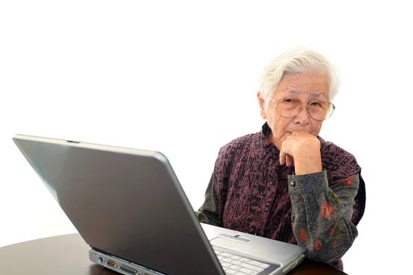 Äldre kvinna med laptop på skrivbordet — Stockfoto