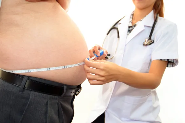 Ernsthafter Arzt untersucht Fettleibigkeit eines Patienten Stockfoto