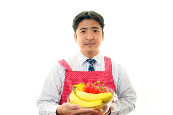 Uomo sorridente che tiene frutta — Foto Stock