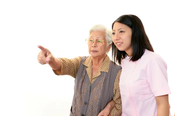 Vriendelijke verpleegster zorgt voor een oudere vrouw — Stockfoto