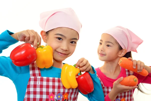 Smiling girls holding vegetables — Stock Photo, Image