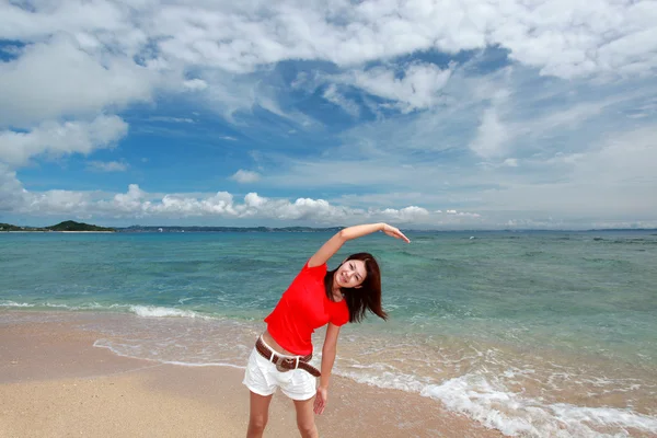 Jeune femme faisant des étirements sur la plage — Photo