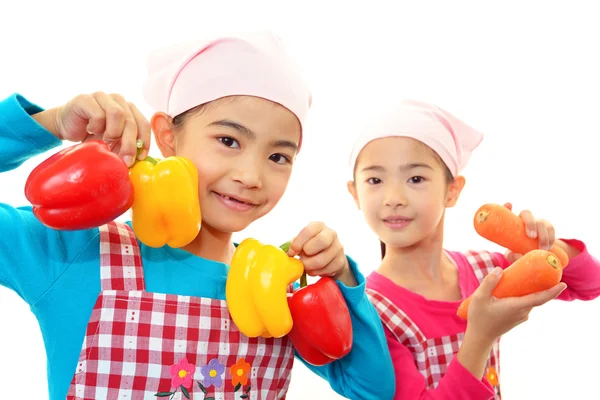 Smiling girls holding vegetables — Stock Photo, Image
