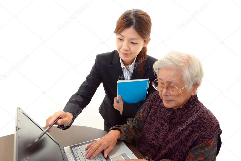 Young woman helping an elderly lady use a computer