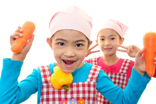 Meninas sorridentes segurando legumes — Fotografia de Stock