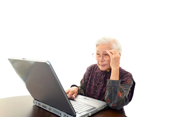 Senior vrouw met laptop aan de balie — Stockfoto