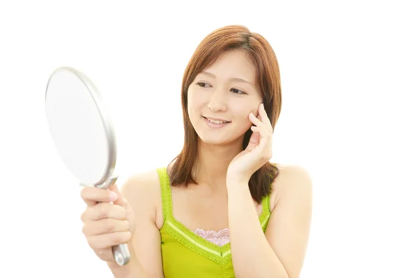 Молодая женщина смотрит на себя в ручное зеркало — стоковое фото