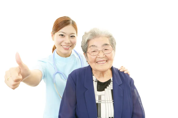 Sorridente medico asiatico e donna anziana — Foto Stock