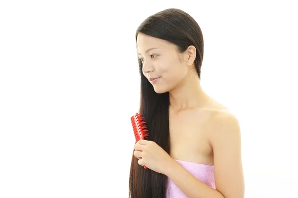 Junge Frau kämmt mit einer Haarbürste — Stockfoto