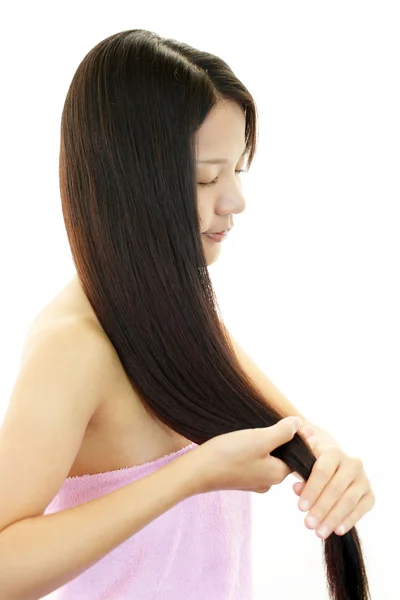 Привлекательная азиатка, ухаживающая за своими волосами — стоковое фото
